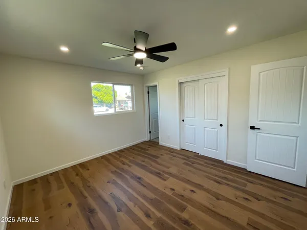 a view of empty room with wooden floor and fan