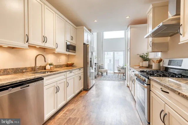a large kitchen with stainless steel appliances granite countertop a lot of counter space and wooden floors