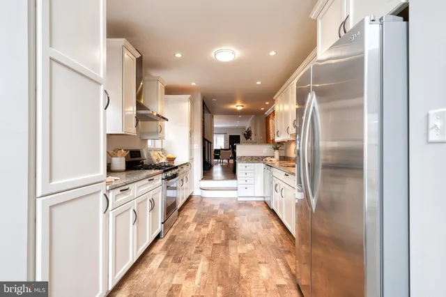 a large kitchen with stainless steel appliances kitchen island a large counter top and a refrigerator