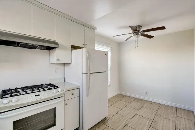 a kitchen with stainless steel appliances a refrigerator a stove and white cabinets
