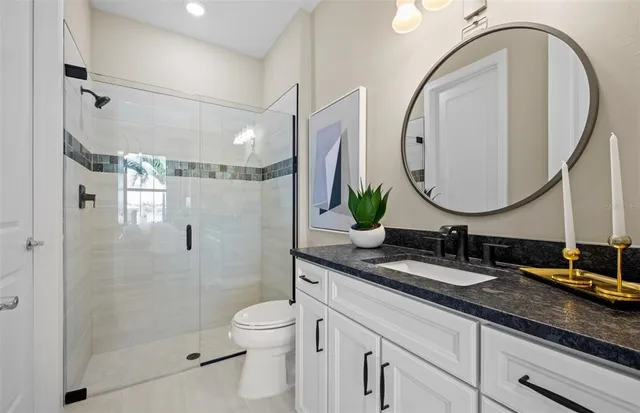 a bathroom with a granite countertop sink a mirror a vanity and a shower