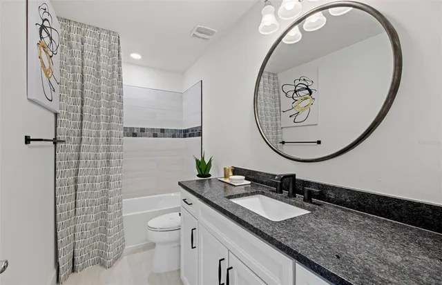 a bathroom with a granite countertop sink a toilet and a mirror