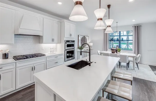 a kitchen with a dining table chairs stainless steel appliances and cabinets