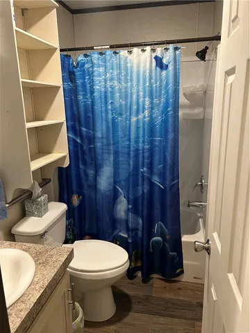 a view of a backyard with brick wall and covered with tall trees