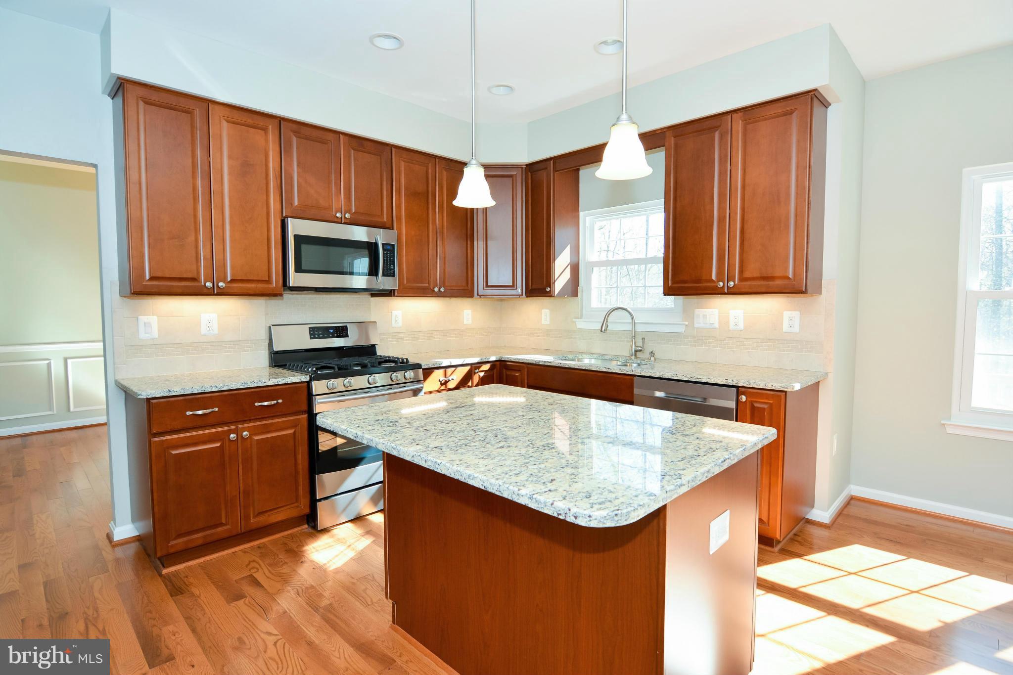 591 Small Reward Road Huntingtown, MD 20639 - Photo 11 of 30 a kitchen with stainless steel appliances granite countertop a sink stove microwave and refrigerator