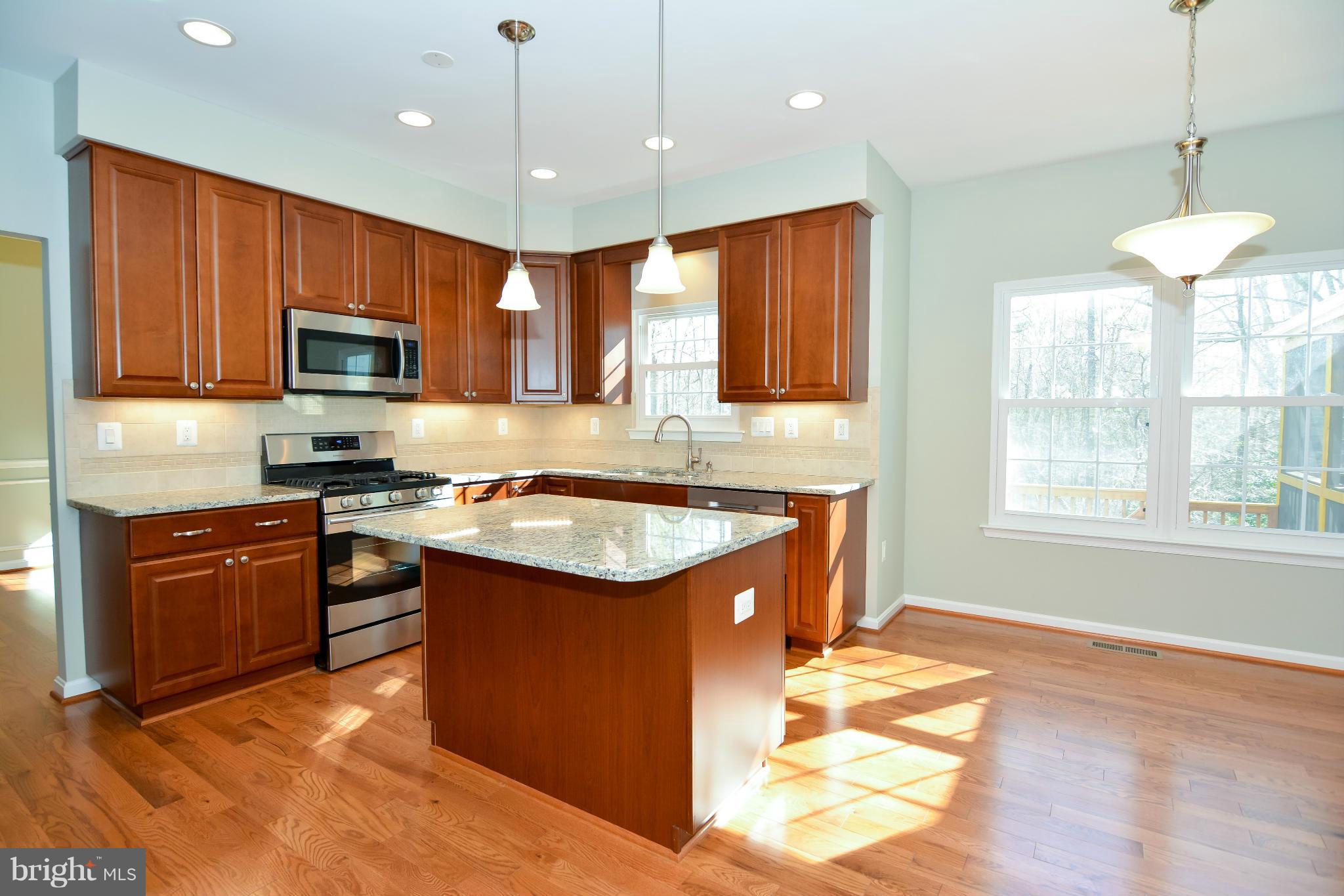 591 Small Reward Road Huntingtown, MD 20639 - Photo 10 of 30 a kitchen with stainless steel appliances granite countertop a stove top oven a sink dishwasher a dining table and chairs with wooden floor
