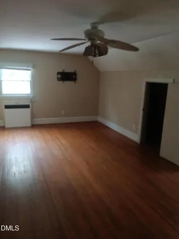 an empty room with wooden floor cabinet and windows