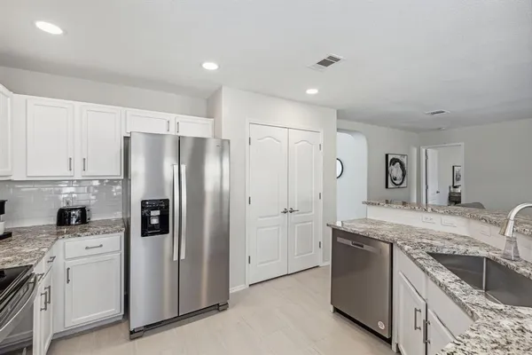 a kitchen with stainless steel appliances granite countertop a refrigerator a sink and white cabinets
