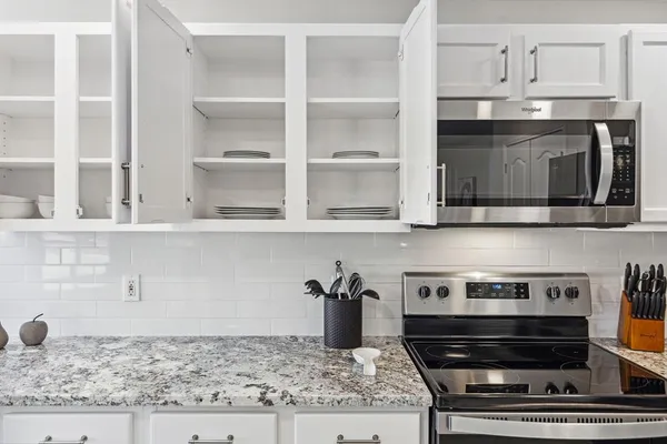 a kitchen with granite countertop a stove a microwave and cabinets