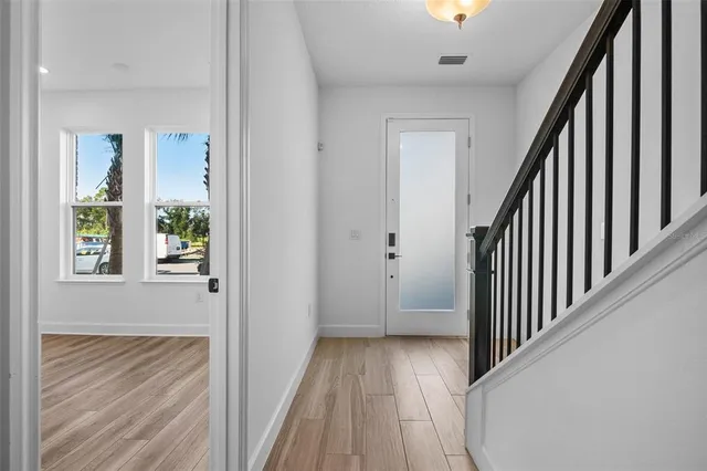 a view of a hallway with wooden floor and stairs
