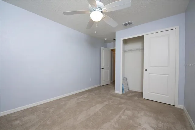 an empty room with closet and a ceiling fan