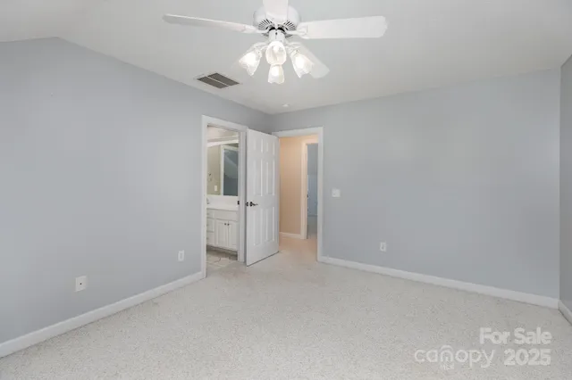 a view of an empty room and chandelier fan