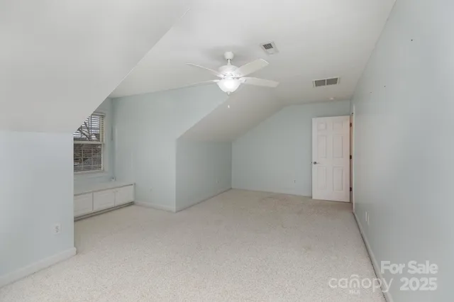 an empty room with chandelier fan and windows