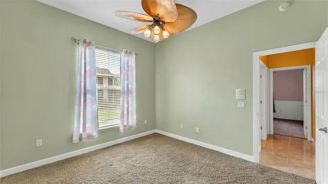 an empty room with a windows and chandelier fan