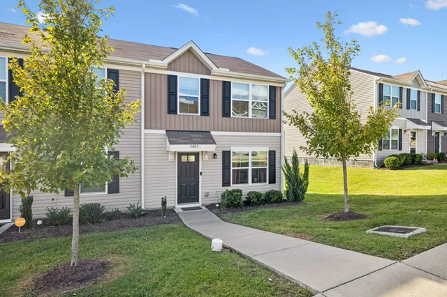 a front view of a house with garden and trees