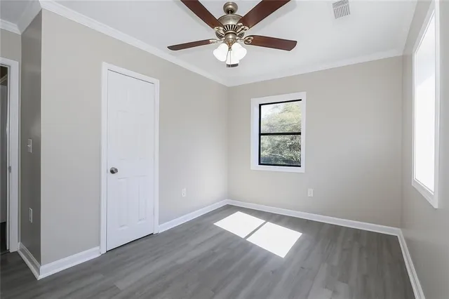 a view of empty room with wooden floor and fan