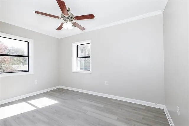 an empty room with wooden floor and windows