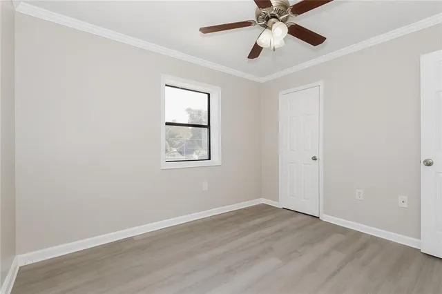 an empty room with wooden floor ceiling fan and windows