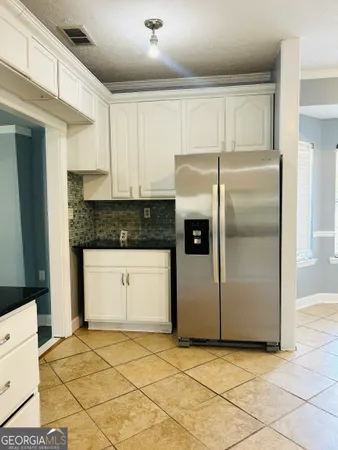 a kitchen with stainless steel appliances granite countertop a refrigerator a sink and white cabinets