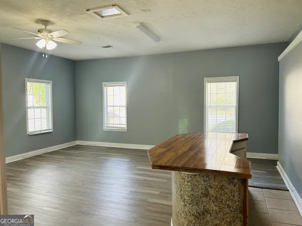 an empty room with wooden floor fan and windows