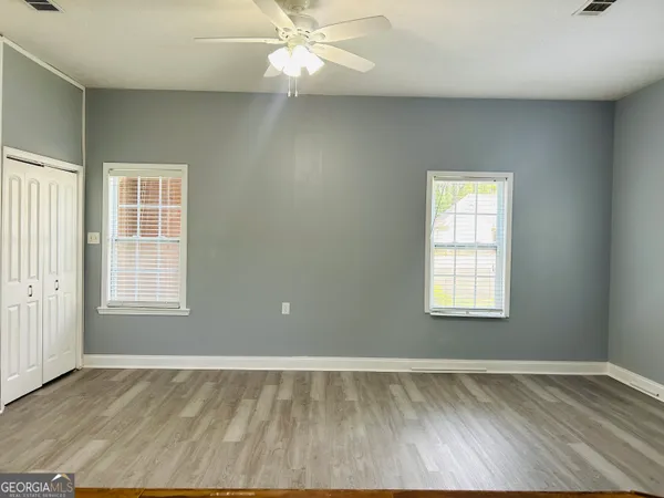 a view of an empty room with wooden floor and a window