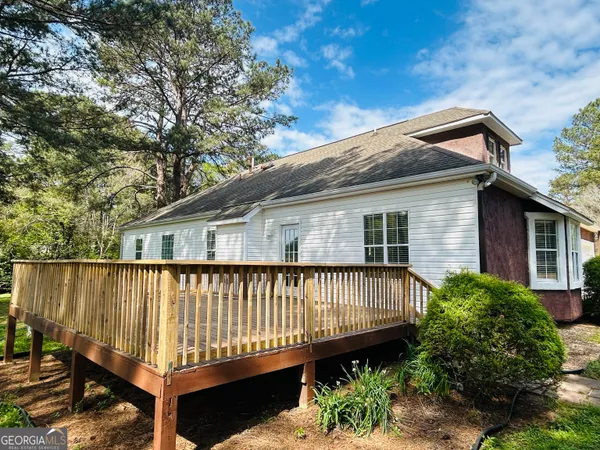 a view of a house with a wooden deck and a yard