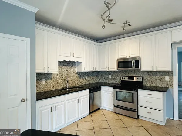 a kitchen with stainless steel appliances granite countertop a stove a sink and a microwave