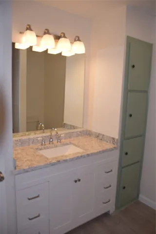 a bathroom with a granite countertop sink and a mirror