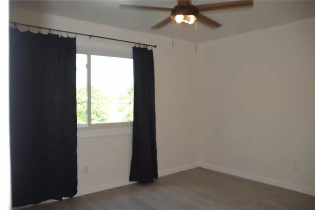 an empty room with a window and a fan