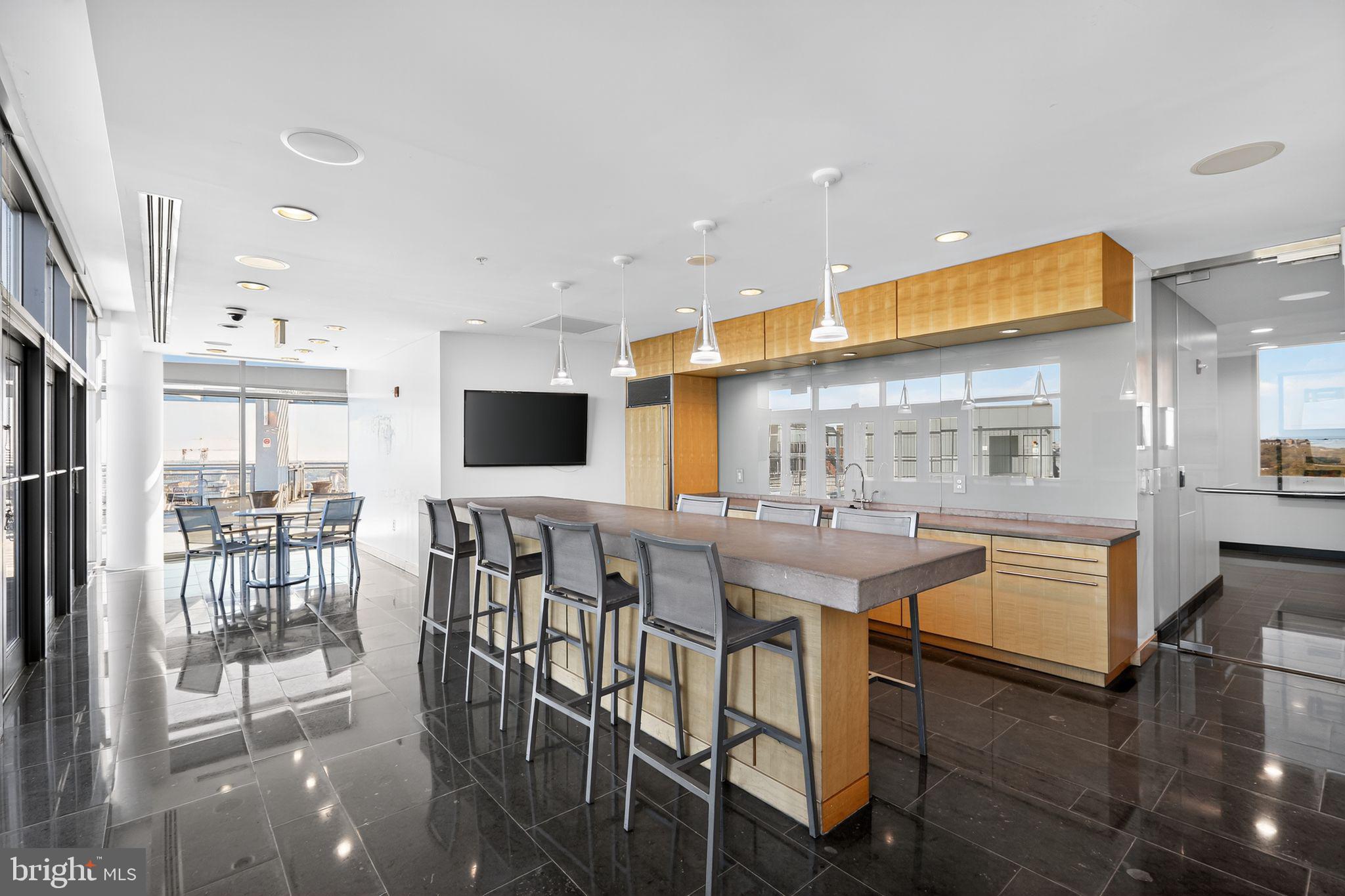 2001 15th Street North, Unit 420 Arlington, VA 22201 - Photo 18 of 27 a kitchen with stainless steel appliances granite countertop a stove top oven a sink a dining table and chairs with wooden floor