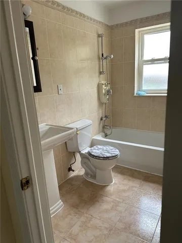 a bathroom with a sink a toilet a tub and a window