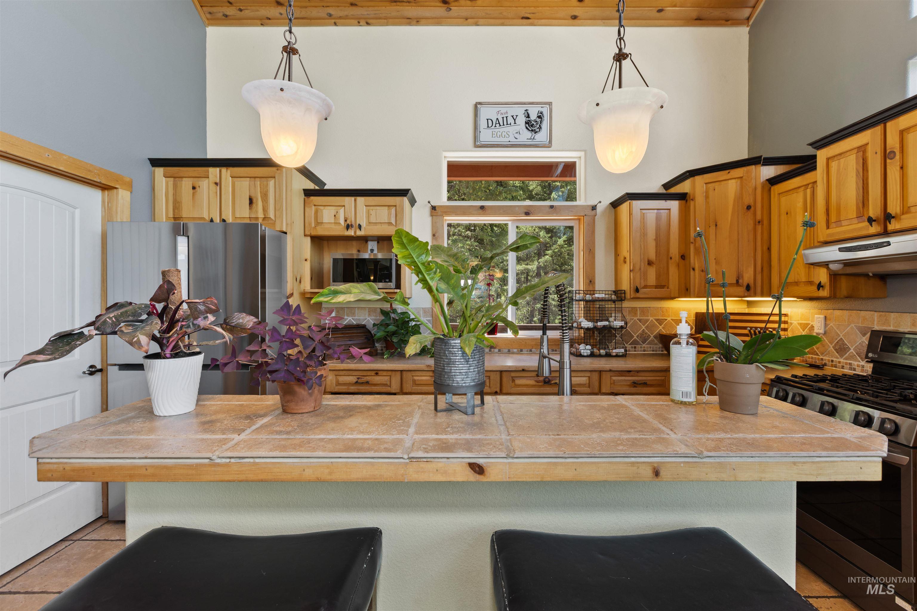 60 Highland Road Boise, ID 83716 - Photo 16 of 42 Kitchen with appliances with stainless steel finishes, a wooden ceiling with exposed beams, a kitchen breakfast bar, a center island with sink, and under cabinet range hood