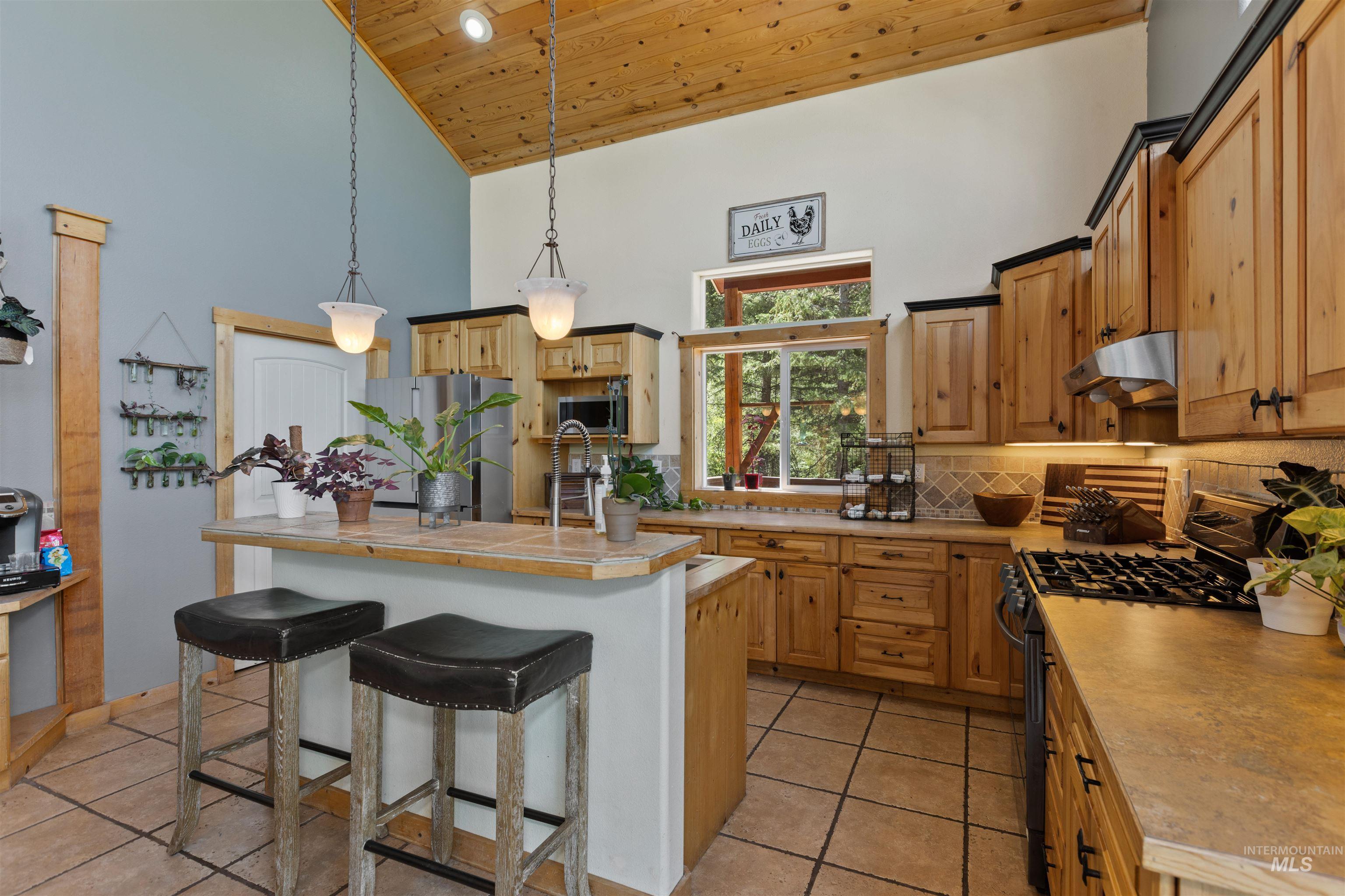 60 Highland Road Boise, ID 83716 - Photo 17 of 42 Kitchen with wooden ceiling, high vaulted ceiling, appliances with stainless steel finishes, light tile patterned floors, and decorative backsplash