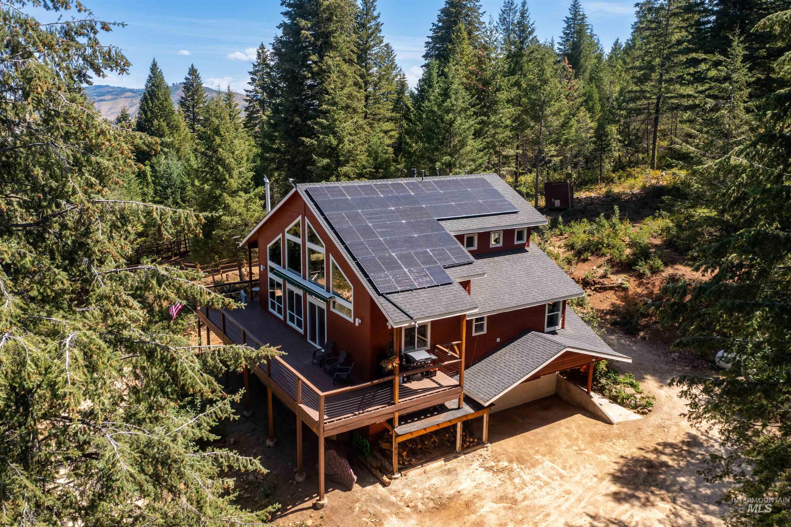 60 Highland Road Boise, ID 83716 - Photo 40 of 42 Back of house with roof mounted solar panels, roof with shingles, a deck, a view of trees, and driveway