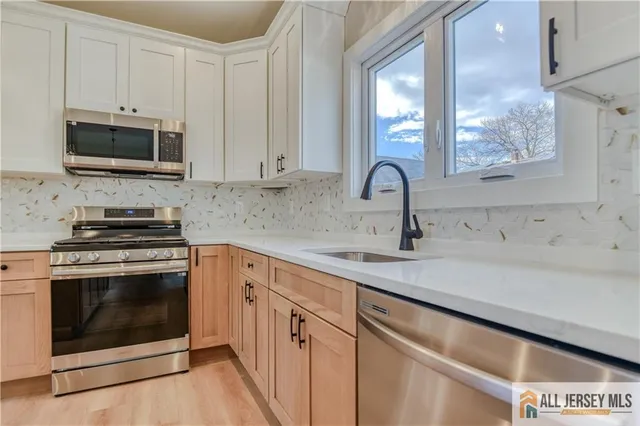 a kitchen with white cabinets stainless steel appliances and sink