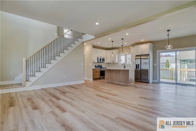 a view of kitchen with kitchen island wooden floor center island and stainless steel appliances