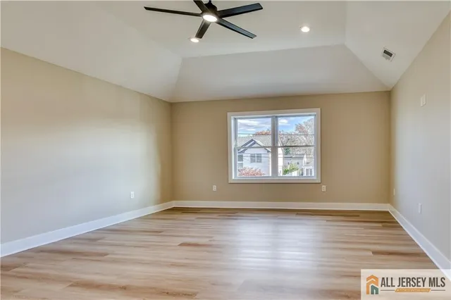 an empty room with wooden floor fan and windows