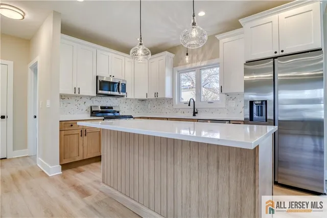 a kitchen with kitchen island granite countertop a sink a counter space stainless steel appliances and cabinets