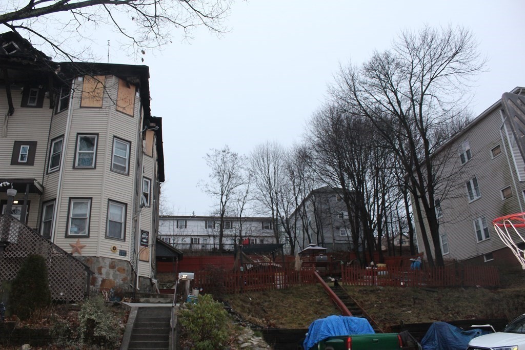 119 Rodney Street Worcester, MA 01605 - Photo 2 of 21 a backyard of a house with wooden fence and large trees