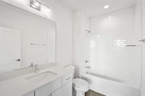 a bathroom with a granite countertop sink a toilet and shower