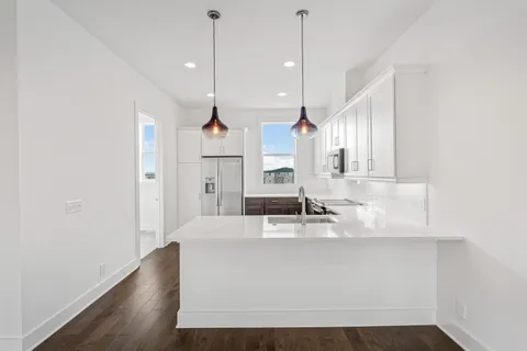 a large white kitchen with wooden floor