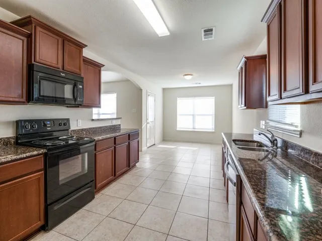 a kitchen with stainless steel appliances granite countertop a stove a sink and a microwave