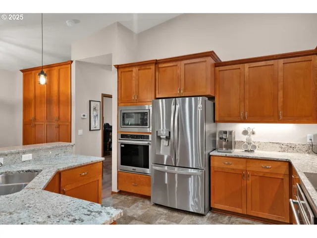 a kitchen with stainless steel appliances granite countertop a refrigerator a sink and a stove