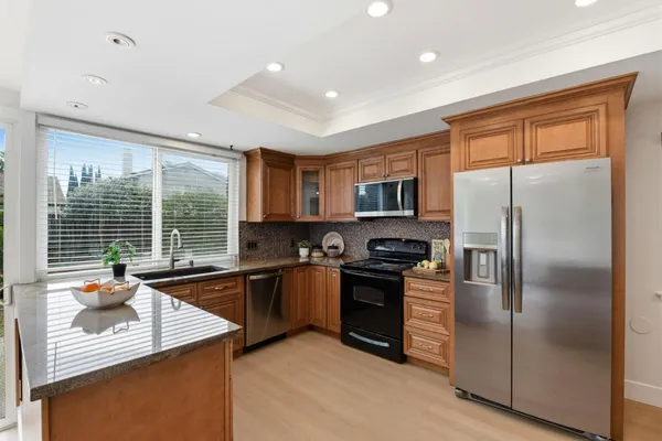 a kitchen with stainless steel appliances granite countertop a refrigerator a sink a stove and oven