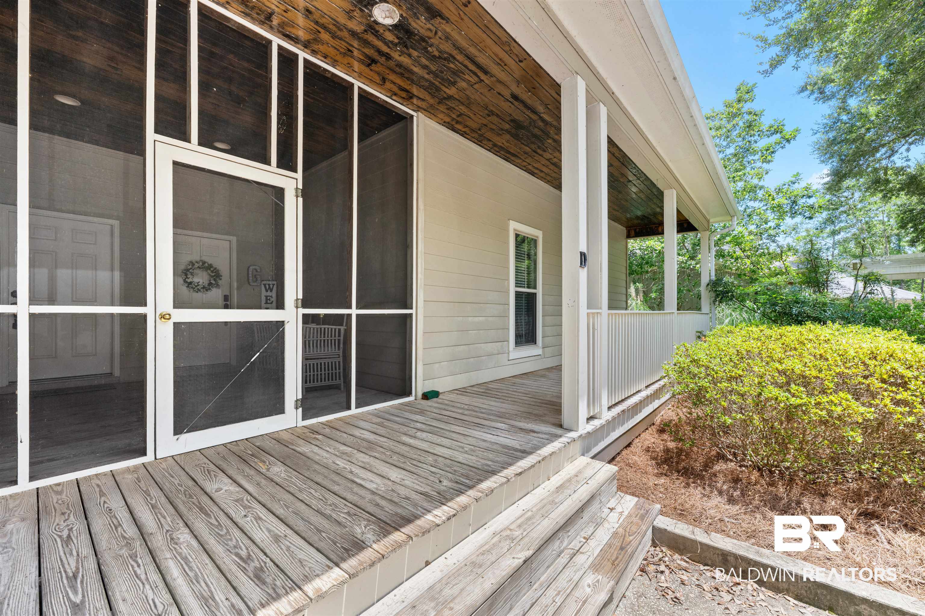 32700 Steelwood Ridge Road, Unit D Loxley, AL 36551 - Photo 24 of 41 Expansive wood-finish deck with multiple steps, leading to a screened porch entrance