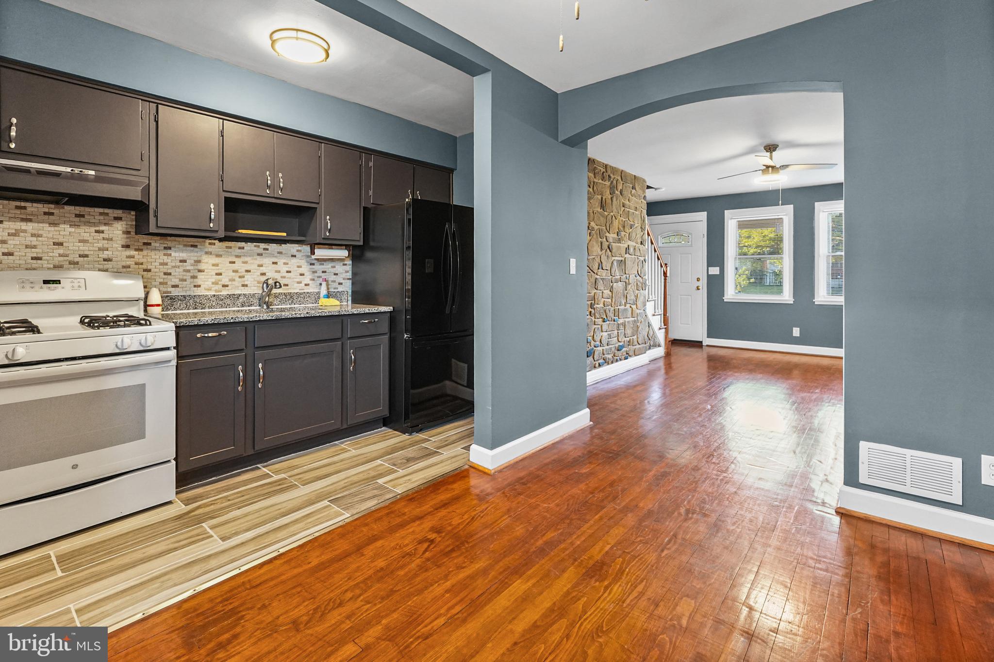 6920 Conley Street Baltimore, MD 21224 - Photo 3 of 12 a kitchen with stainless steel appliances granite countertop a stove cabinets and wooden floor