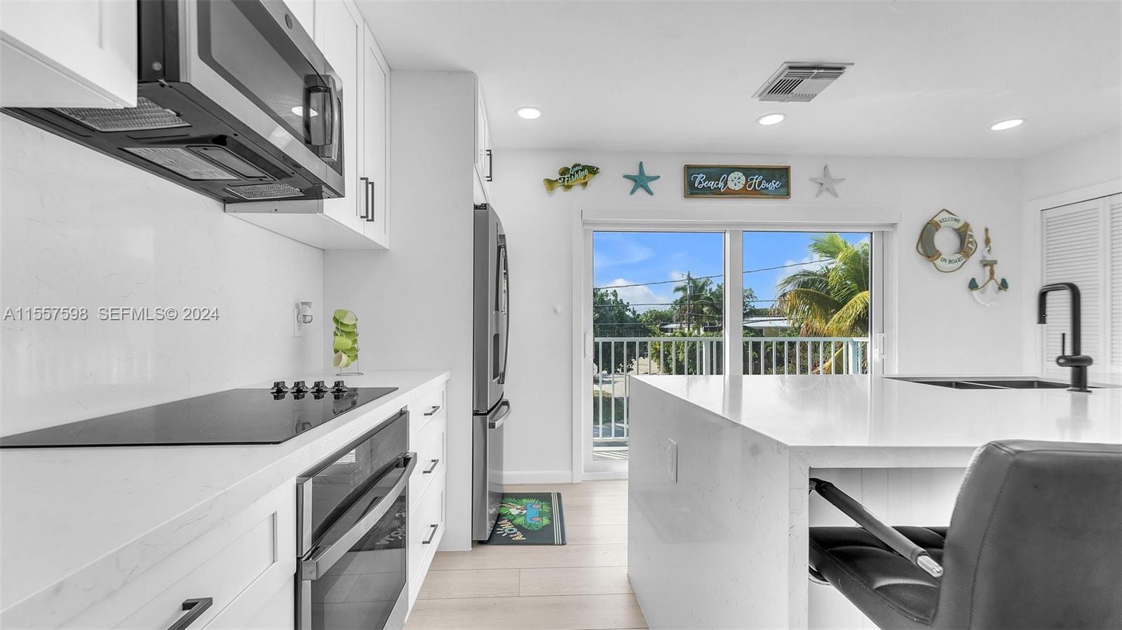 441 La Fitte Road Summerland Key, FL 33042 - Photo 53 of 81 a kitchen with stainless steel appliances a sink a stove a refrigerator a dining table and chairs with wooden floor
