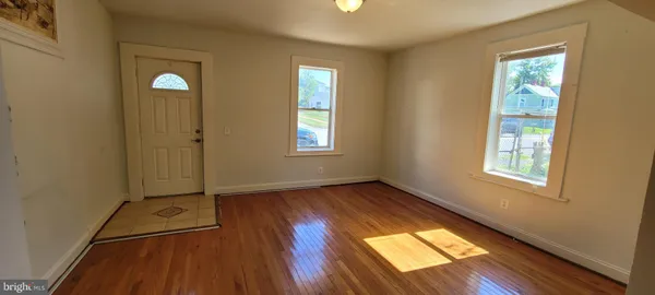 an empty room with wooden floor cabinet and windows