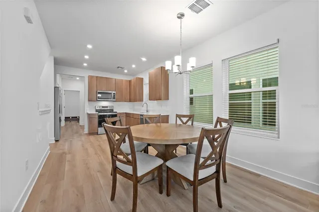 a dining room filled chandelier and wooden floor