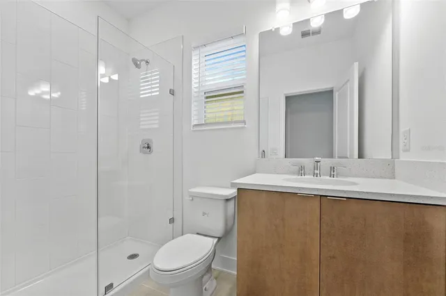 a bathroom with a granite countertop sink toilet a mirror and shower